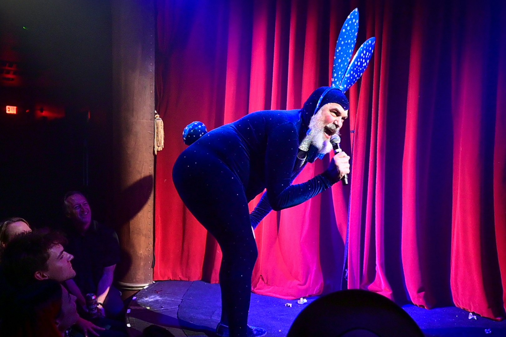 Performer in blue costume with bunny ears on stage at Miss Behaves: Maverick's Variety Show.
