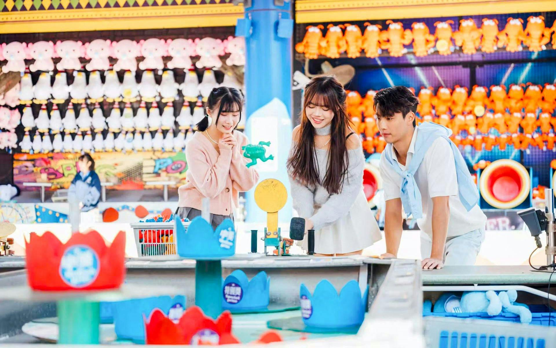 Visitors playing a game at Ocean Park souvenir shop with plush toys in the background.