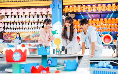 Visitors playing a game at Ocean Park souvenir shop with plush toys in the background.