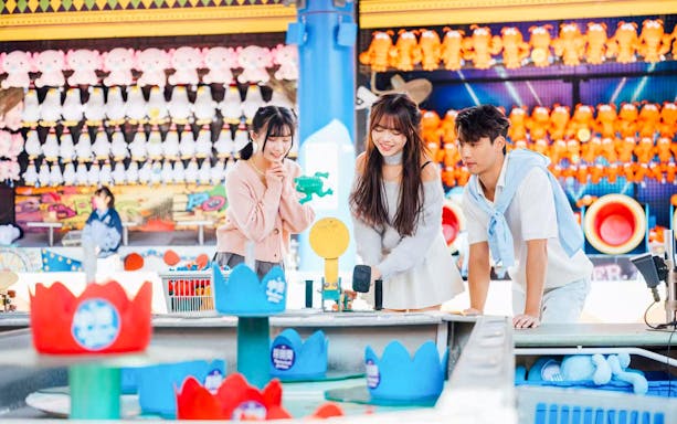 Visitors playing a game at Ocean Park souvenir shop with plush toys in the background.