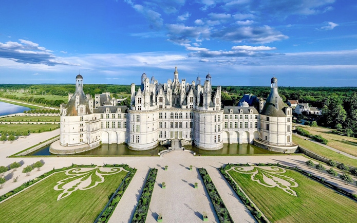 Chambord Castle with symmetrical gardens and surrounding greenery in France.