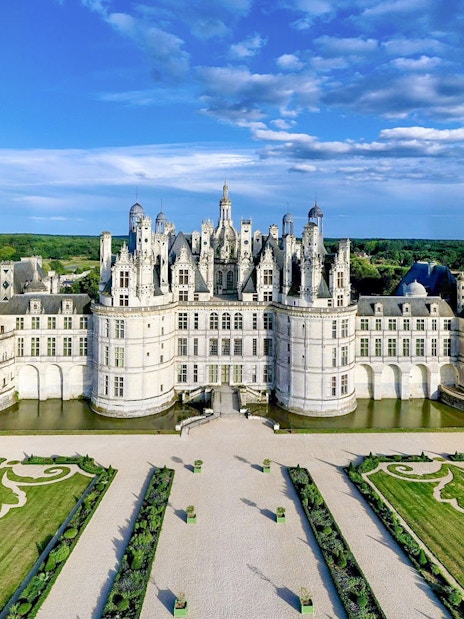 Chambord Castle with symmetrical gardens and surrounding greenery in France.