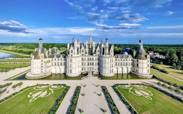 Chambord Castle with symmetrical gardens and surrounding greenery in France.