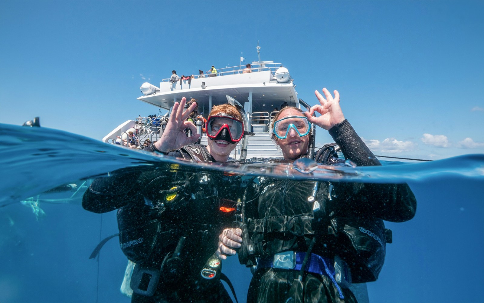 Snorkelers giving OK sign near boat at Outer Great Barrier Reef, Cairns trip.