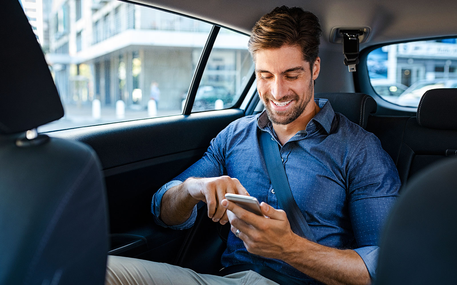 Businessman in car using smartphone.