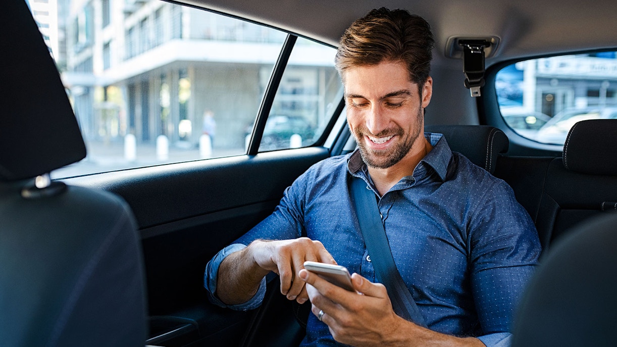 Businessman in car using smartphone.