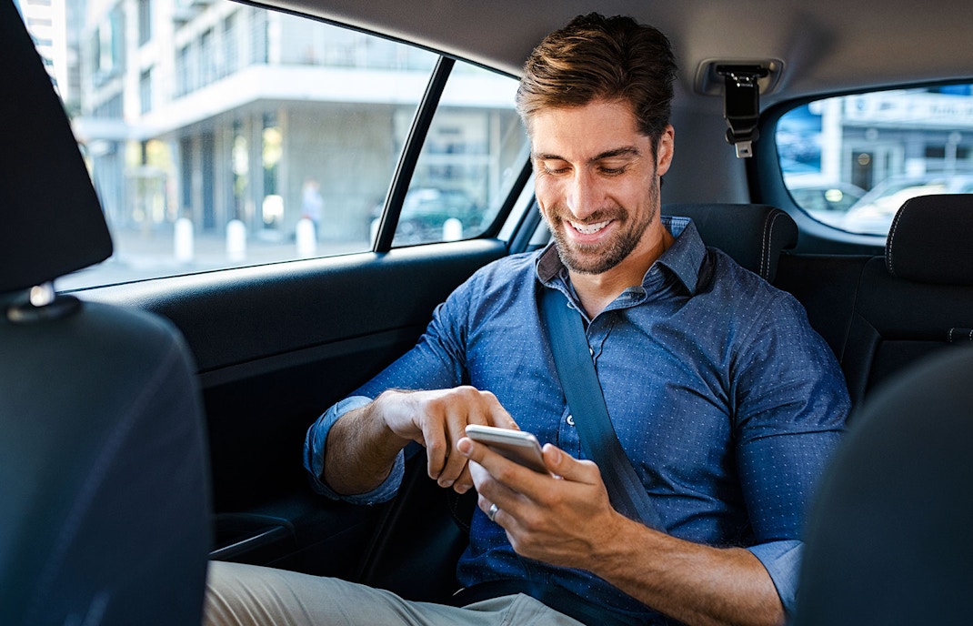 Businessman in car using smartphone.