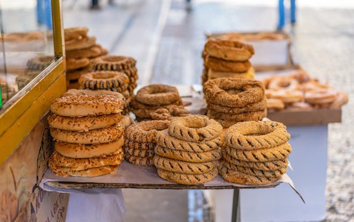 Stacks of traditional Greek sesame bread rings on a street vendor's table in Athens.