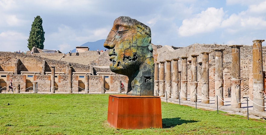Pompeii ruins with modern sculpture and ancient columns in Italy.