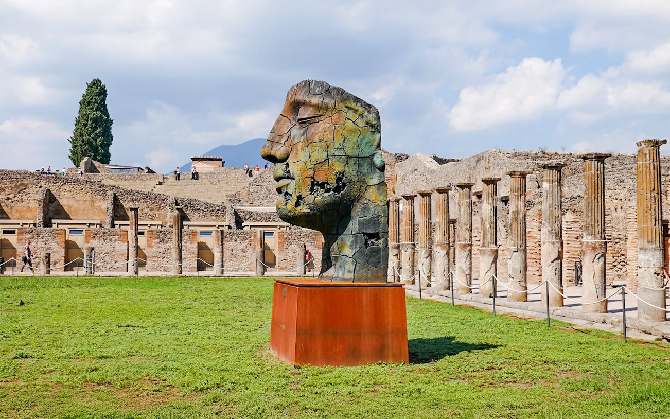 Pompeii ruins with modern sculpture and ancient columns in Italy.