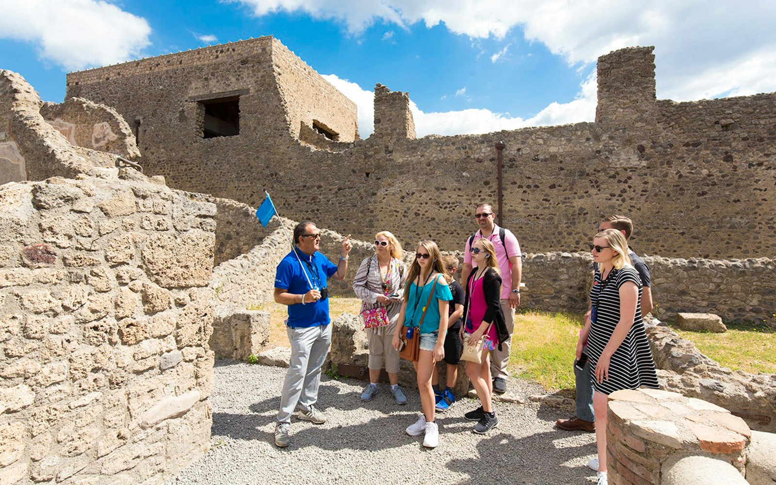 Tour guide leading tourists through ancient ruins of Herculaneum on a half-day tour.