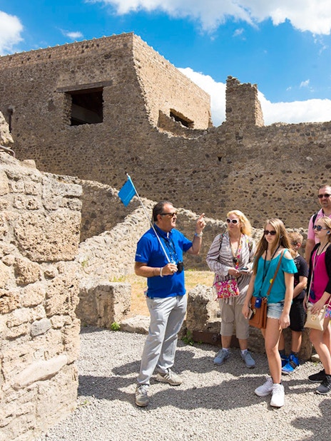 Tour guide leading tourists through ancient ruins of Pompeii, Italy on a half-day tour.