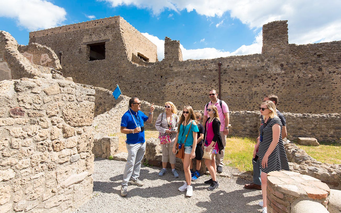 Tour guide leading tourists through ancient ruins of Pompeii, Italy on a half-day tour.