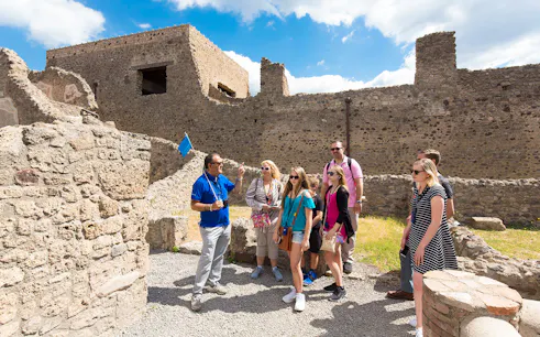 Tour guide leading tourists through ancient ruins of Pompeii, Italy on a half-day tour.