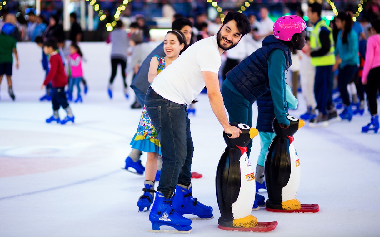 People ice skating with penguin aids at Dubai Ice Rink.