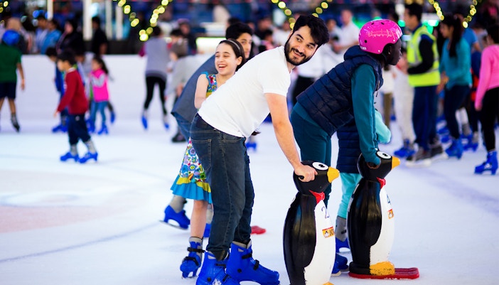People ice skating with penguin aids at Dubai Ice Rink.