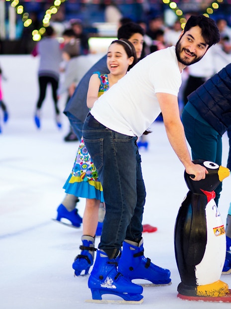 People ice skating with penguin aids at Dubai Ice Rink.