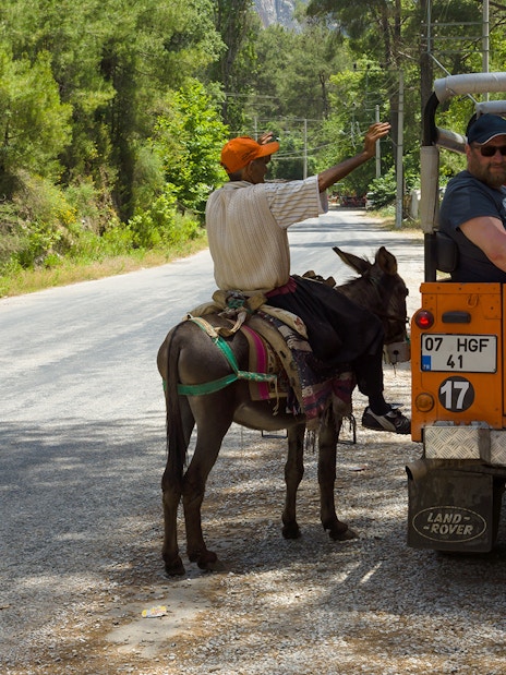 Jeep safari group interacting with a local on a donkey in Antalya countryside.
