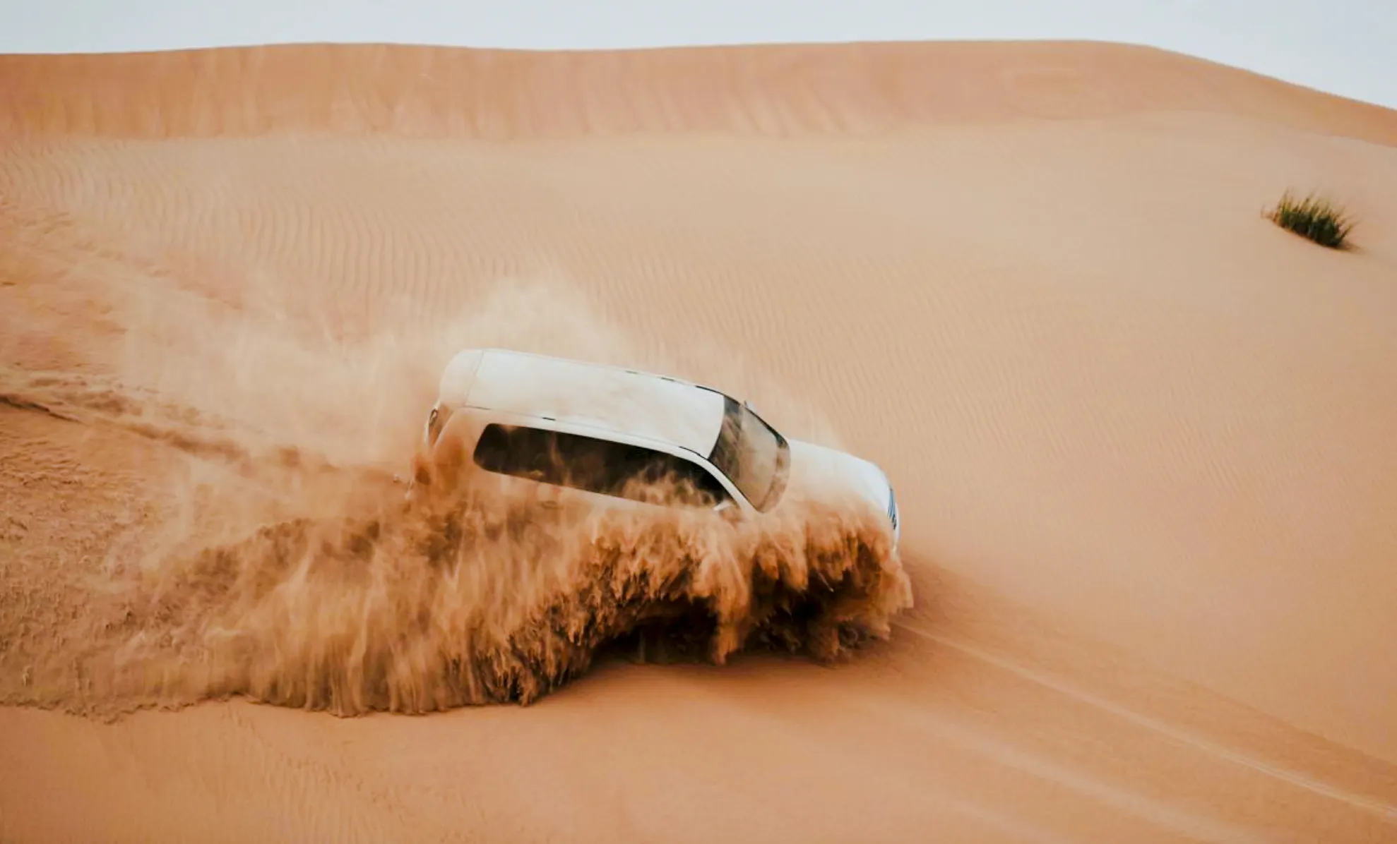 SUV driving through sand dunes during Abu Dhabi Evening Desert Safari.