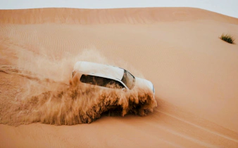 SUV driving through sand dunes during Abu Dhabi Evening Desert Safari.