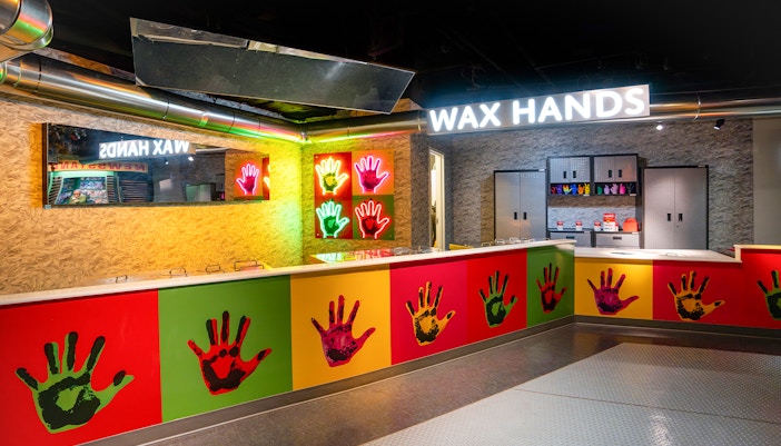 Wax Hands station at Madame Tussauds New York with colorful handprints and neon signs.
