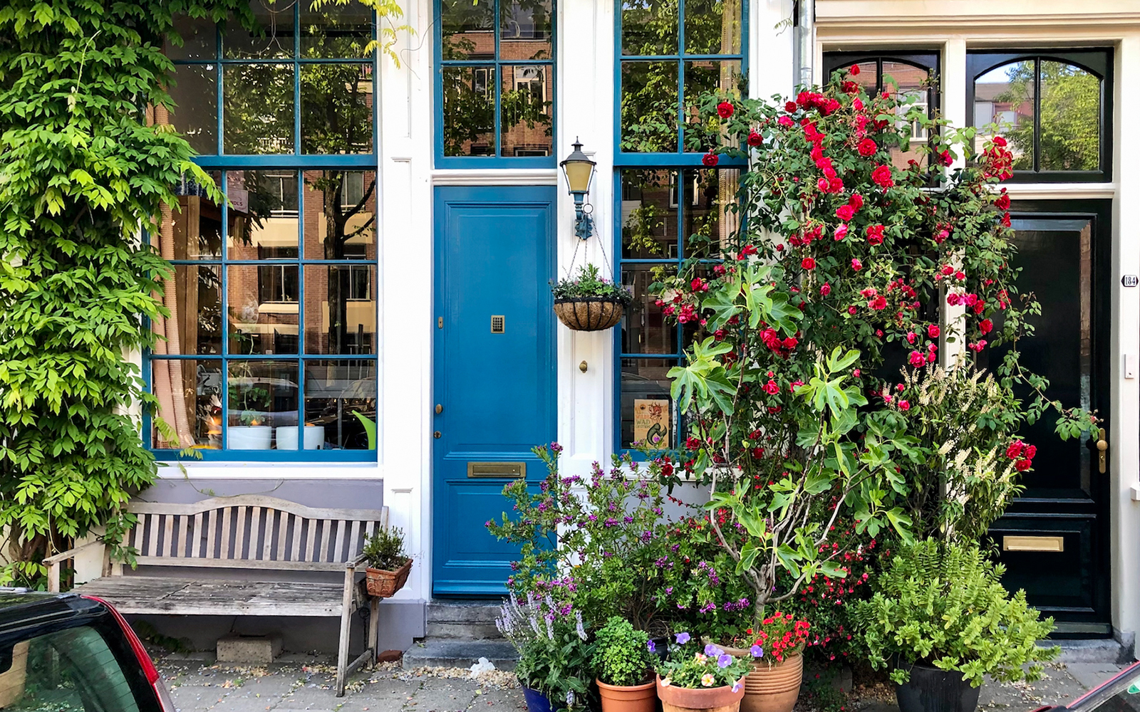 Charming Amsterdam house facade with blue door and vibrant flowers.