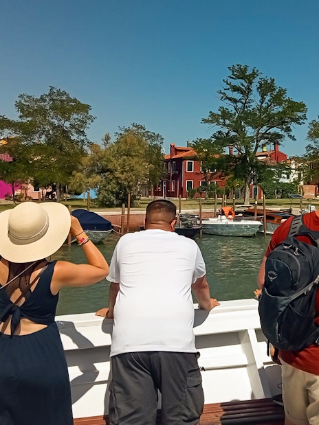 Tourists on a vaporetto viewing colorful houses on Burano Island, Venice.