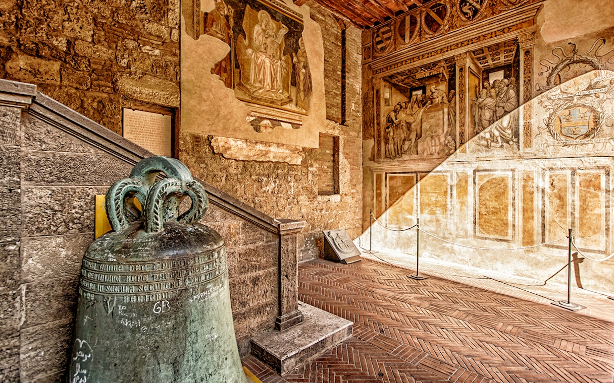 Volterra museum interior with ancient bell and frescoes, part of Combo: Volterra Pass + San Gimignano Pass + San Pietro Museum Tickets.