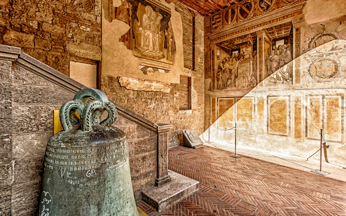 Volterra museum interior with ancient bell and frescoes, part of Combo: Volterra Pass + San Gimignano Pass + San Pietro Museum Tickets.