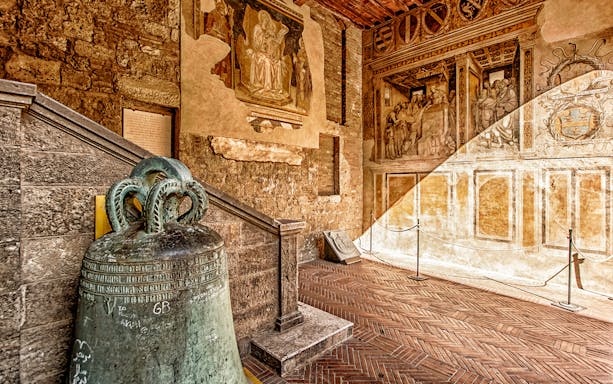 Volterra museum interior with ancient bell and frescoes, part of Combo: Volterra Pass + San Gimignano Pass + San Pietro Museum Tickets.