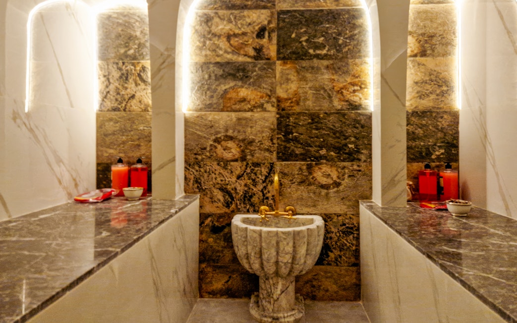 Traditional Hammam interior with marble sink and benches in Marrakesh spa.