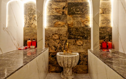 Traditional Hammam interior with marble sink and benches in Marrakesh spa.