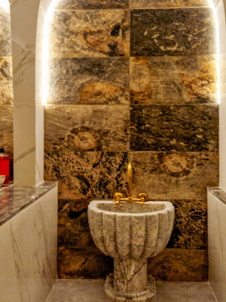 Traditional Hammam interior with marble sink and benches in Marrakesh spa.