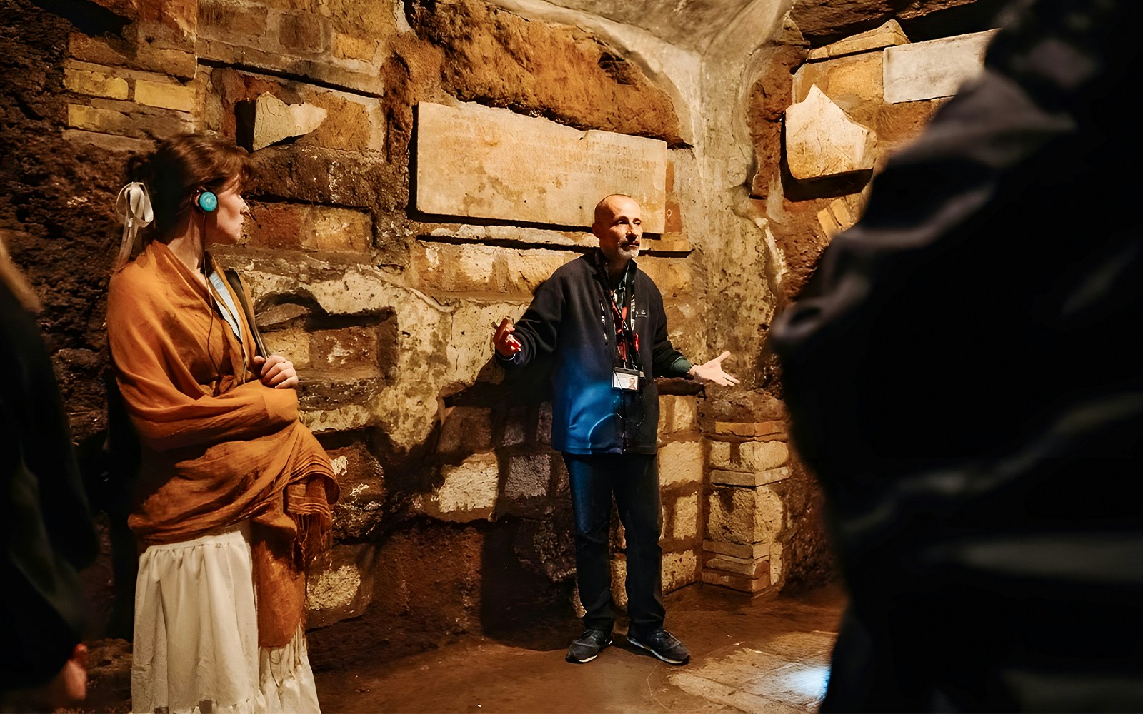 Guide explaining Roman Catacombs to tourists during Capuchin Crypts tour.
