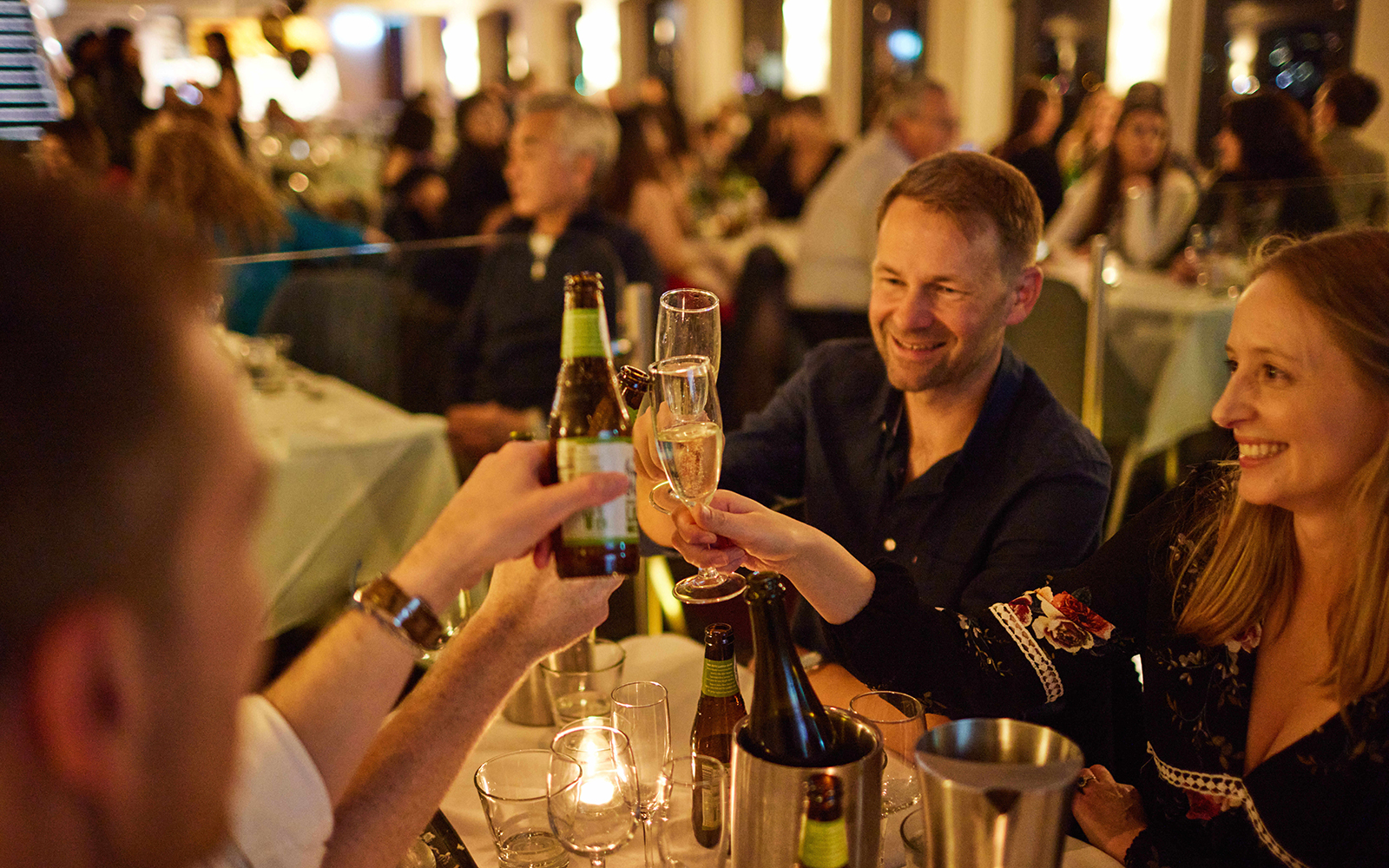 Guests toasting with drinks during a cabaret cruise dinner.