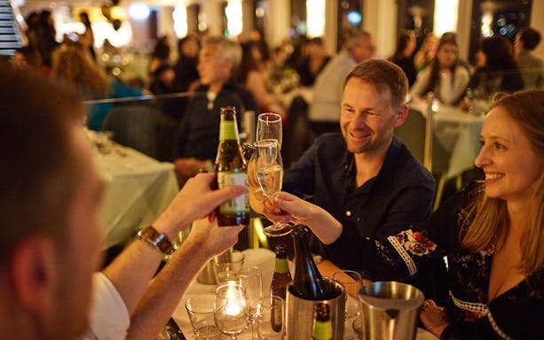 Guests toasting with drinks during a cabaret cruise dinner.