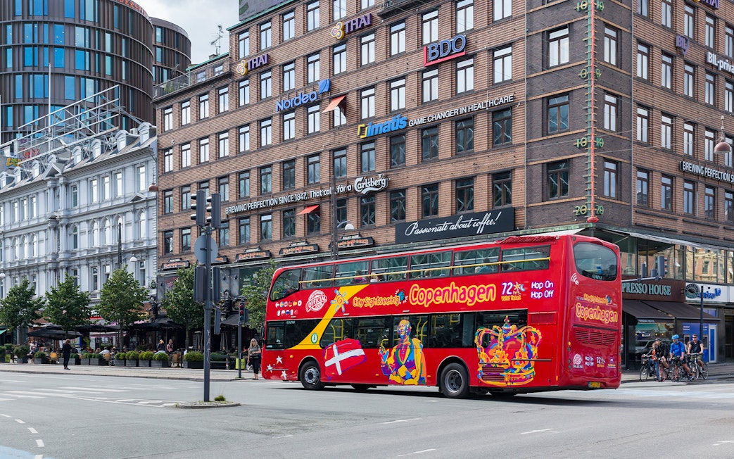 Copenhagen hop-on-hop-off tour bus passing by city buildings.