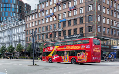Copenhagen hop-on-hop-off tour bus passing by city buildings.