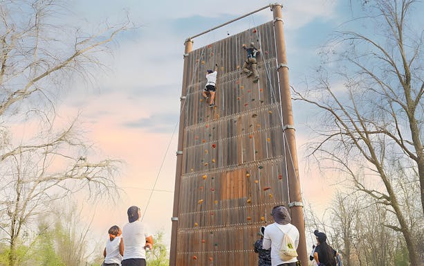 Friends rock climbing at Aventura Parks on a tall outdoor wall.