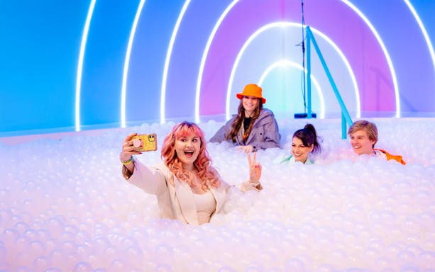 Visitors enjoying The Pool at Upside Down Amsterdam with colorful lights.