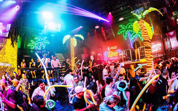 Crowded dance floor at Coco Bongo Congo Bar with neon palm tree lights and partygoers.