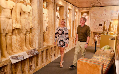 Visitors exploring the Tomb of the Pharaohs exhibit with ancient Egyptian statues and sarcophagus.