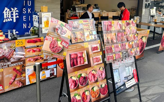 Food stall menu displays at Tsukiji Market, featuring sushi and seafood options.
