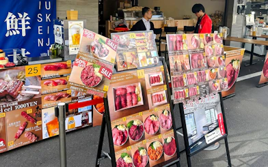 Food stall menu displays at Tsukiji Market, featuring sushi and seafood options.