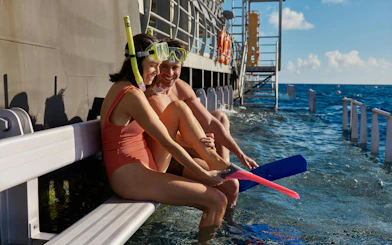 Snorkelers preparing to enter the water from a boat on the Whitehaven Beach tour, Whitsundays.
