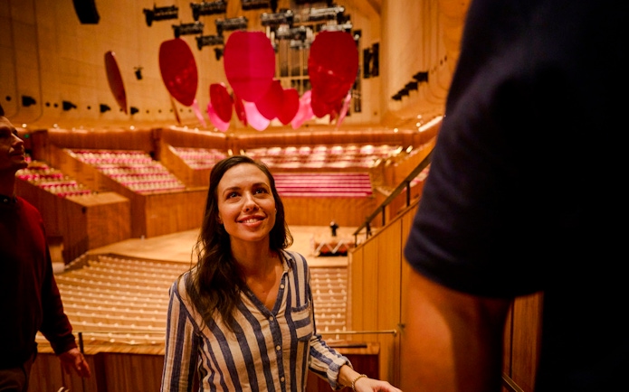Visitor on a guided tour inside Sydney Opera House, admiring the concert hall.