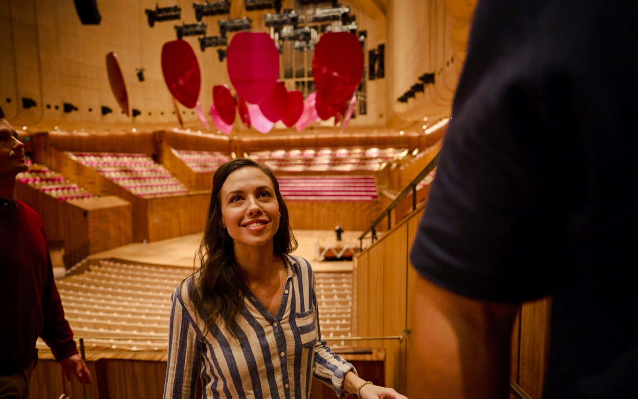 Visitor on a guided tour inside Sydney Opera House, admiring the concert hall.