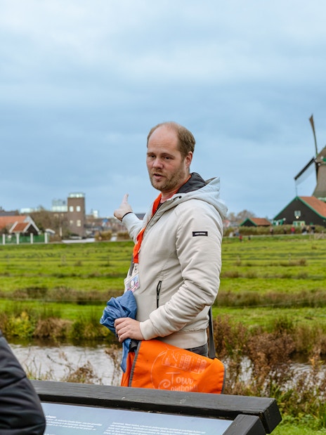 Tour guide pointing at windmills in Keukenhof, Netherlands.