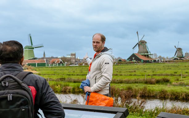 Tour guide pointing at windmills in Keukenhof, Netherlands.