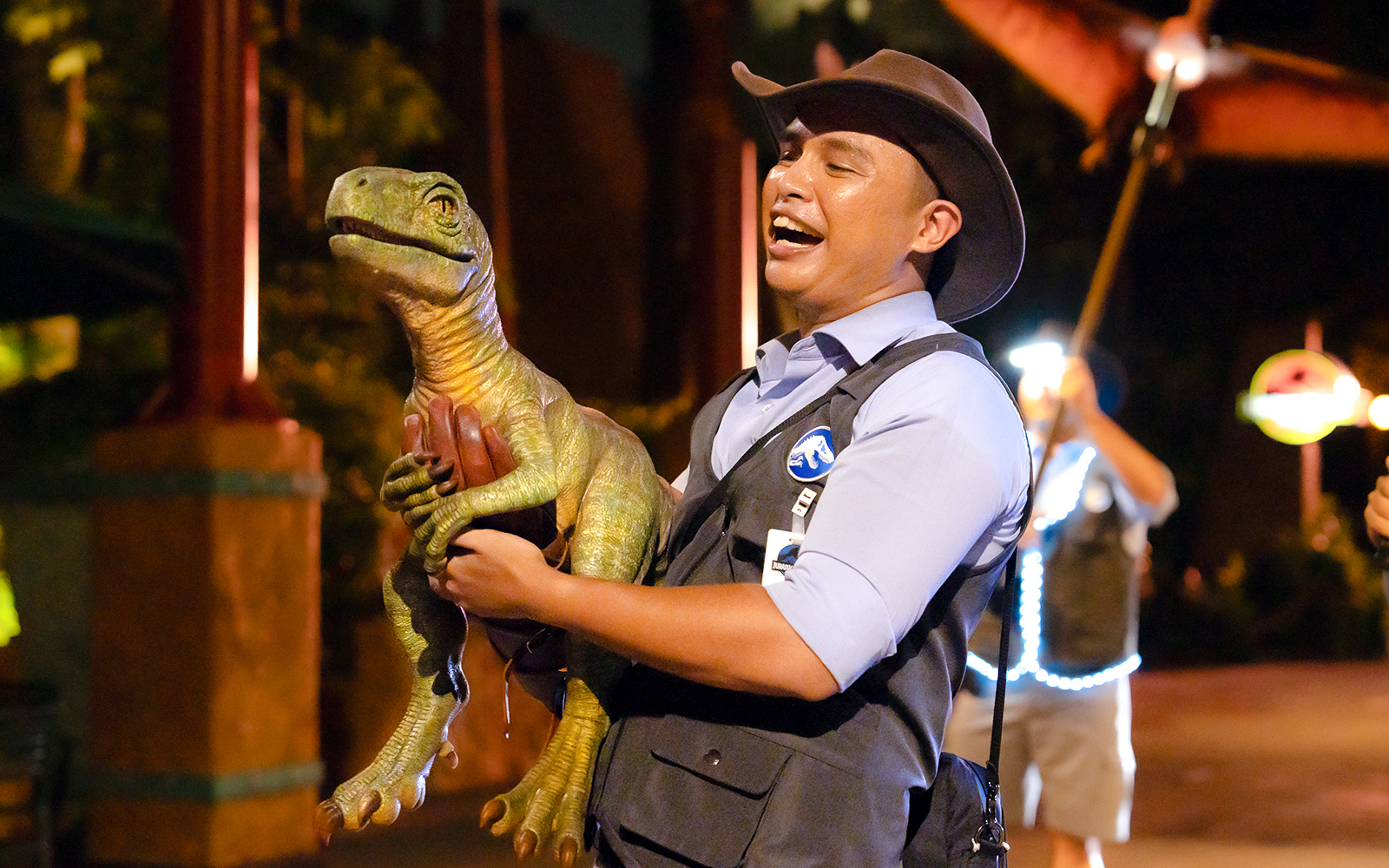 Man holding a dinosaur puppet at Universal Studios Singapore.
